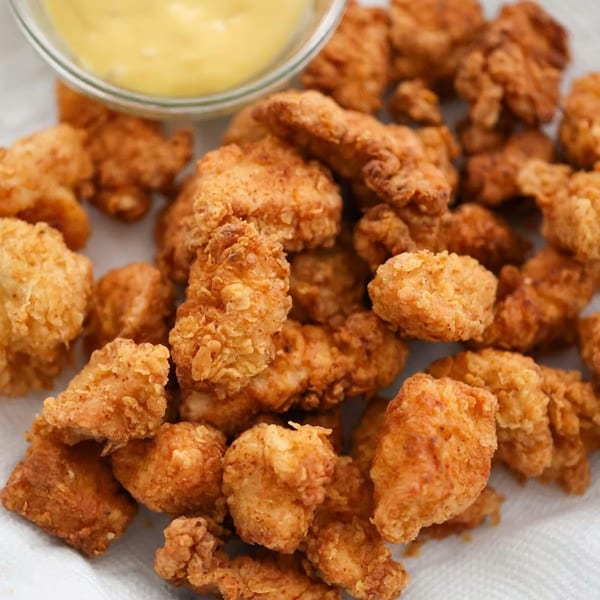 Crispy fried chicken bites with a small bowl of honey mustard dipping sauce.