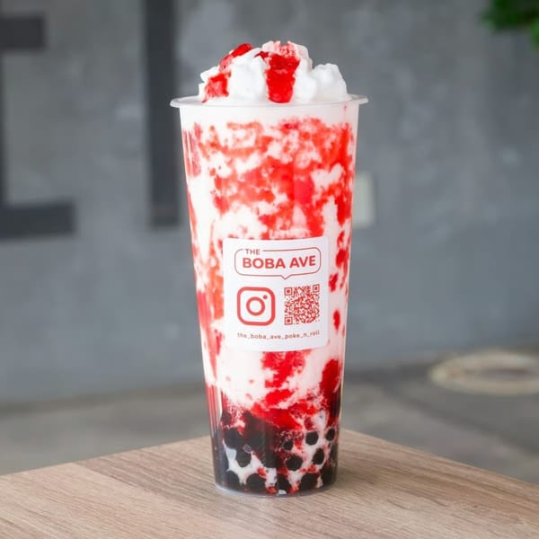A strawberry boba drink from The Boba Ave, topped with whipped cream and strawberry syrup.